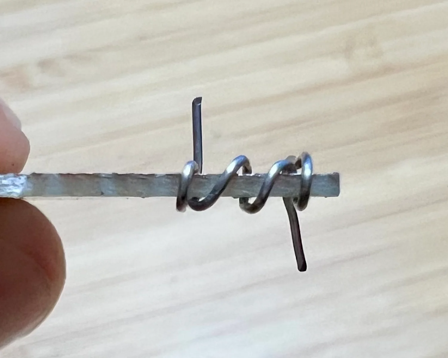 Top-down photo of wire laced over the edge of a PCB.