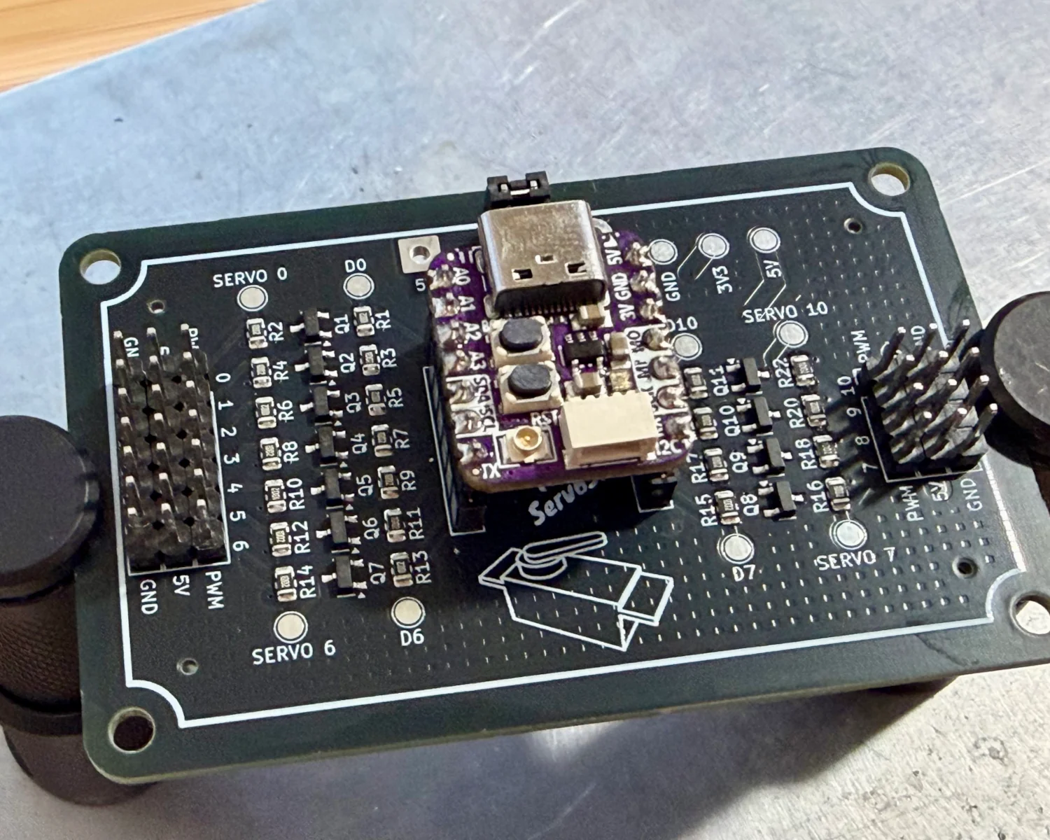 An Oops! All Servos! board, connected to an Adafruit QT Py board.