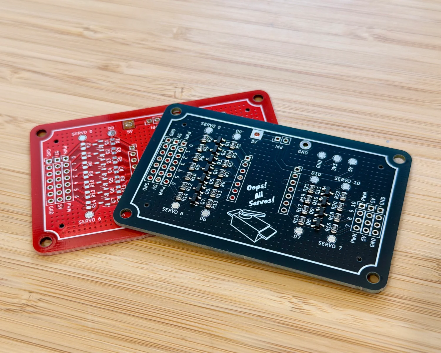 A red, unassembled, PCB and a black, partially assembled, PCB